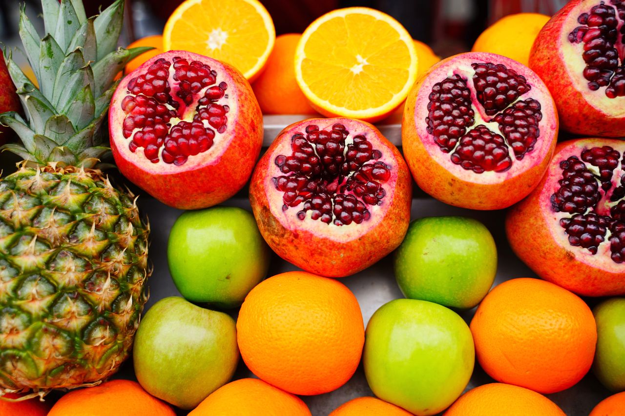 A colorful assortment of fresh fruits including pomegranates, oranges, and apples, ideal for healthy eating themes.